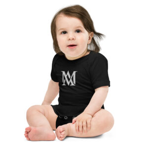 Baby sitting in black onesie with logo