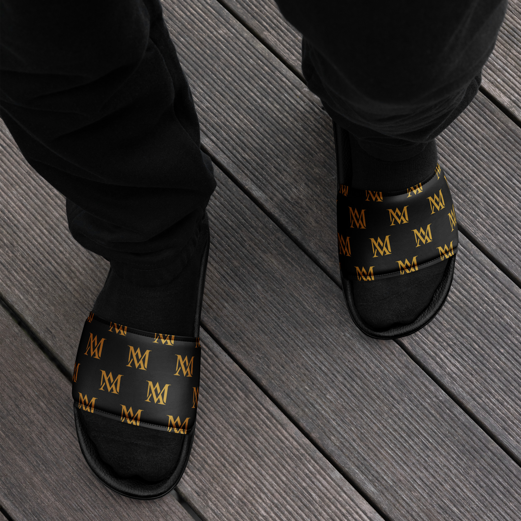 Feet in black slides with gold monogram