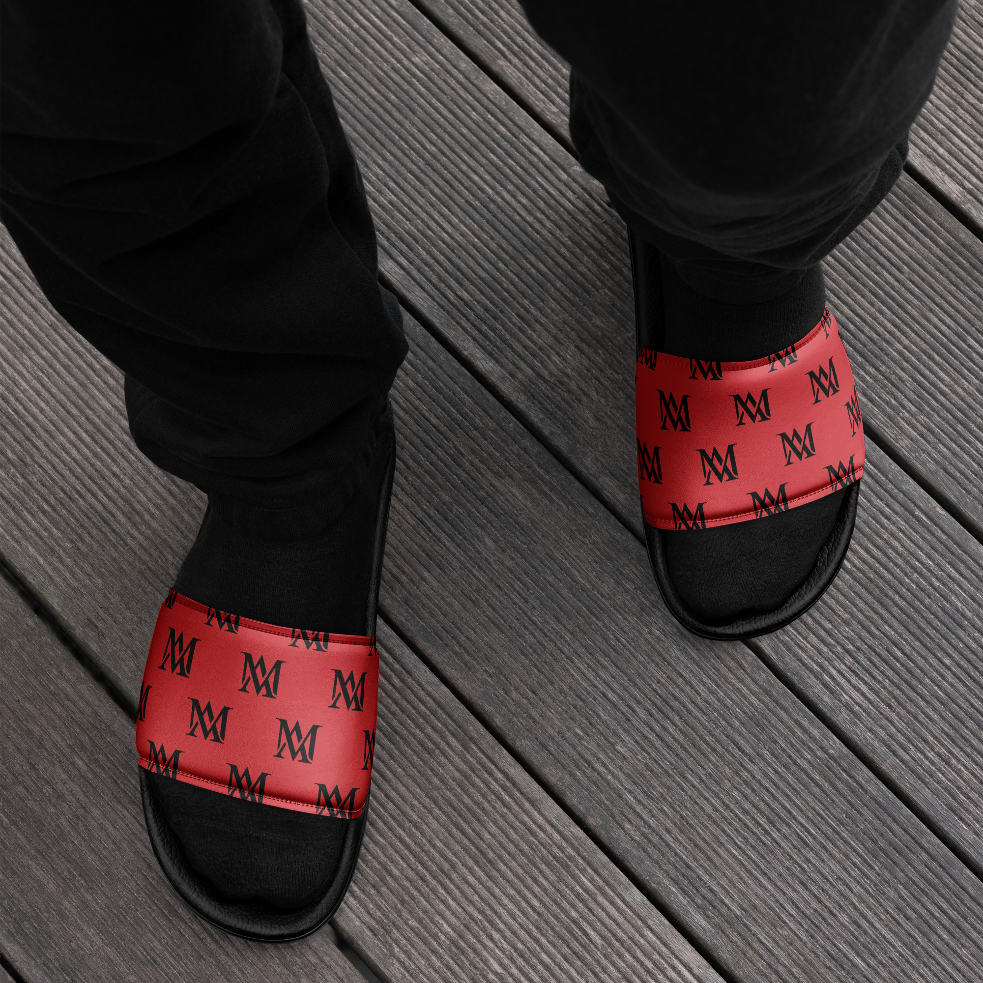 Feet in red monogrammed slides on wooden deck