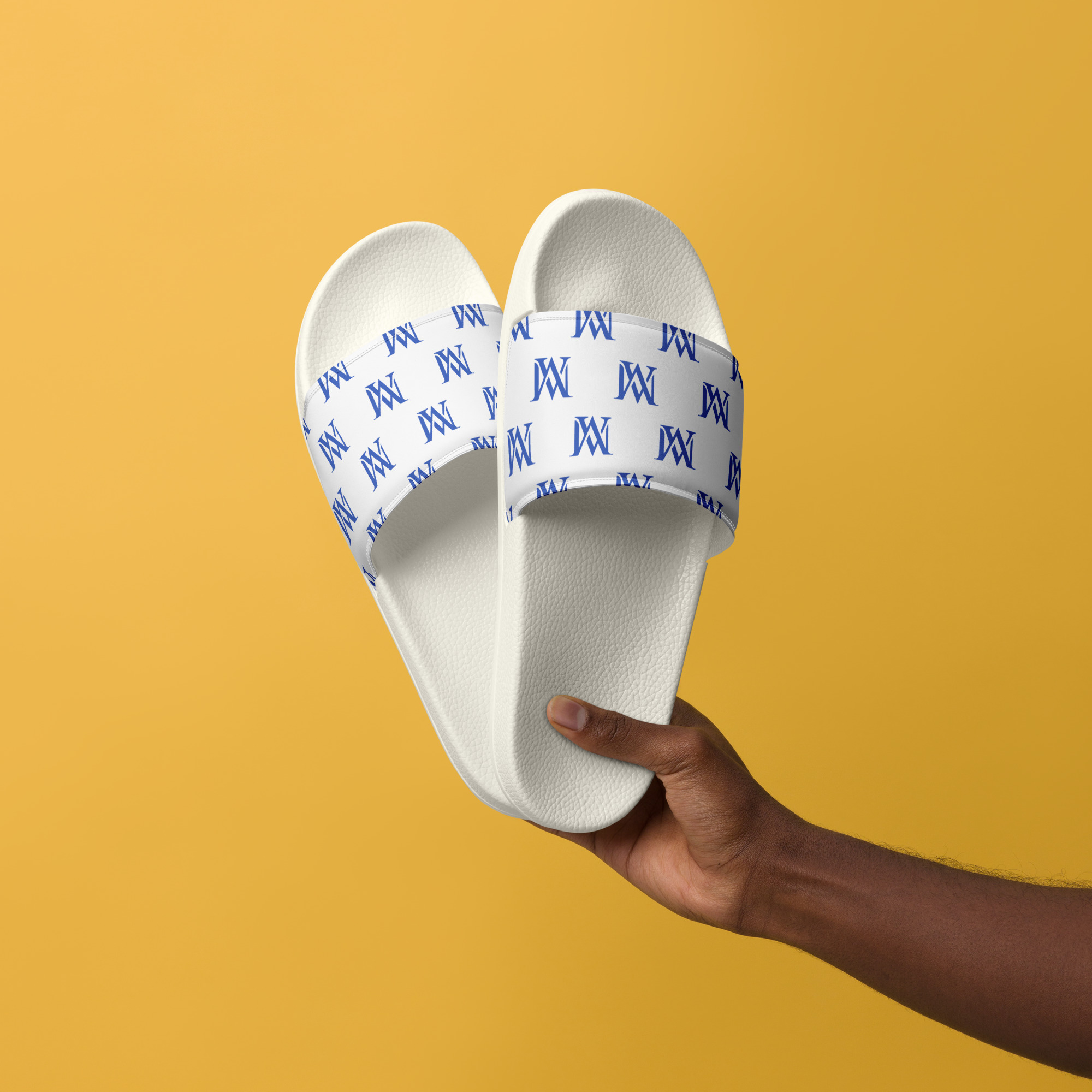 White monogram slide sandals against yellow background
