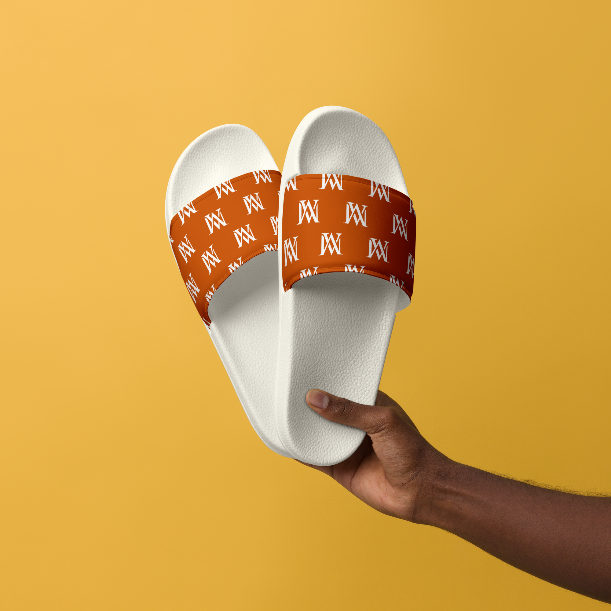 Hand holding white slides with orange monogram straps